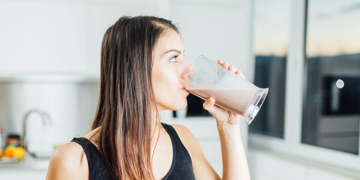 Woman in sportswear drinking chocolate protein shake
